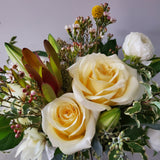 creamy whites and pale yellows with greenery in ceramic vase