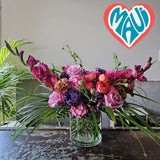 bright pink and purple flowers with tropical foliage in glass vase